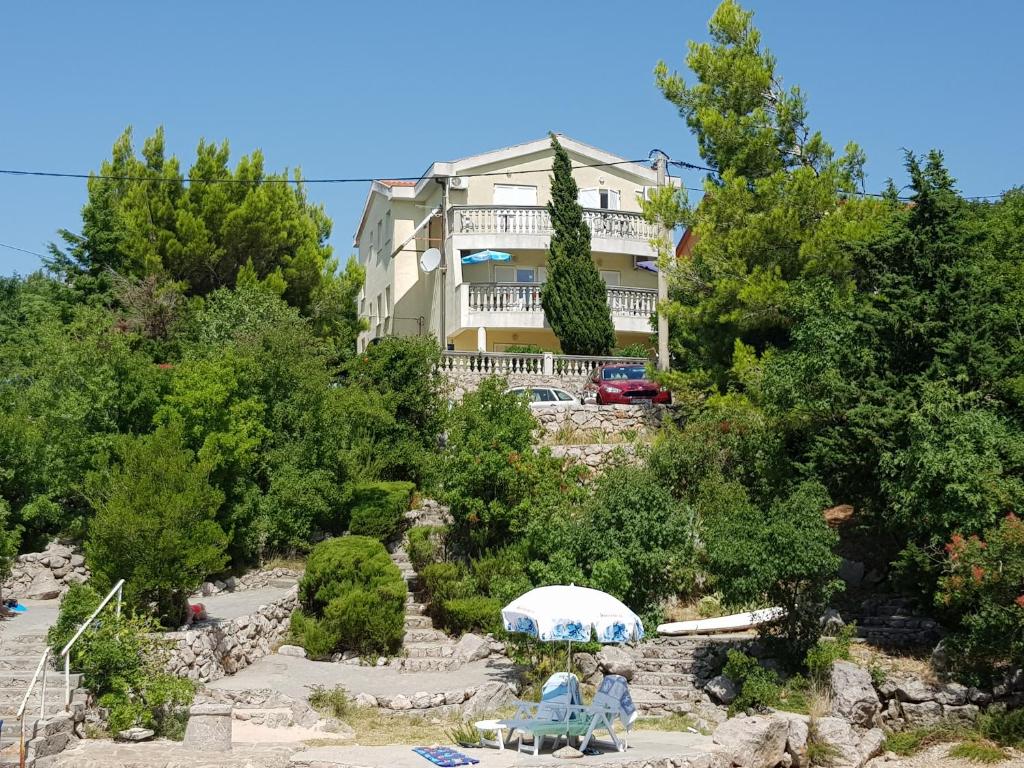 a house on top of a hill with trees at Apartments Akiki in Karlobag