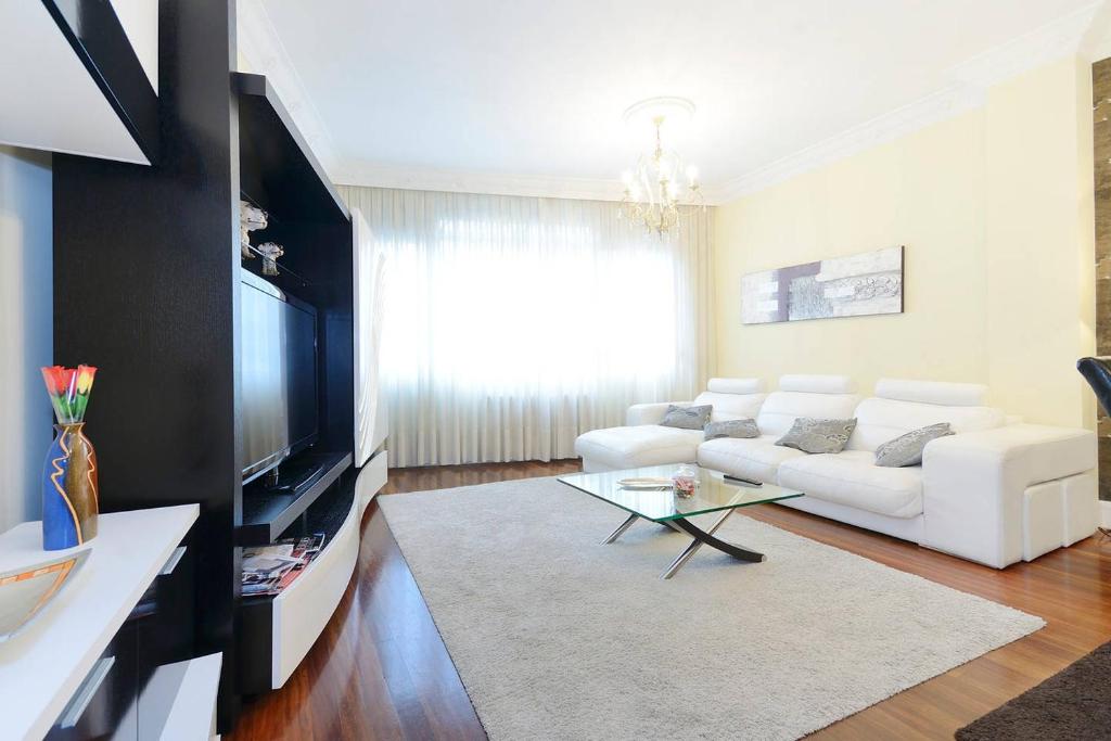 a living room with a white couch and a tv at Apartamento frente al Guggenheim con wifi y parking privado gratis in Bilbao
