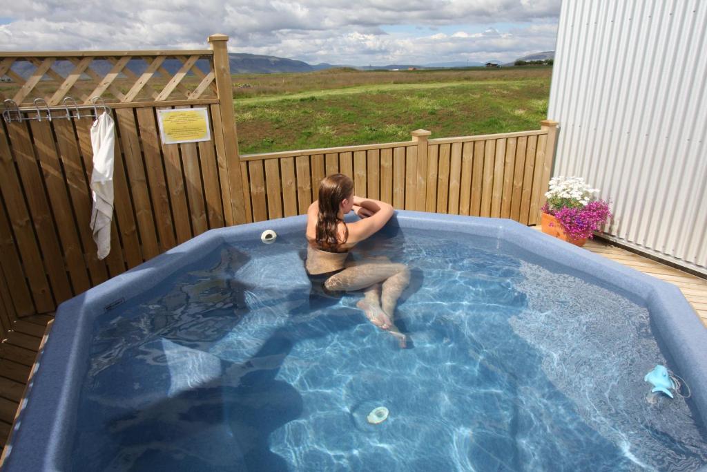 a woman is sitting in a hot tub at Lambastadir Guesthouse in Selfoss