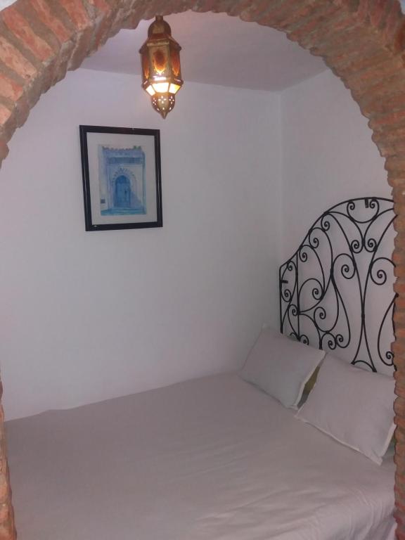 een slaapkamer met een bed met een smeedijzeren hoofdeinde bij Dar naya in Chefchaouene