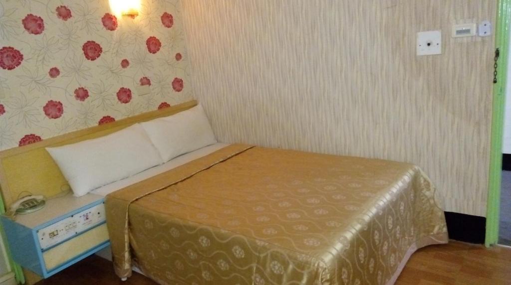 um pequeno quarto com uma cama num quarto em Reui Chung Hotel em Kaohsiung