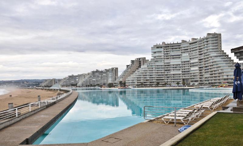 uma grande piscina ao lado de uma praia com grandes edifícios em Sn Alfonso del Mar Edif.Goleta em Algarrobo