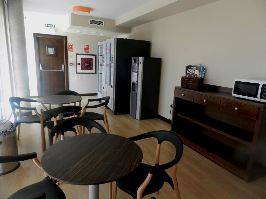 a room with two tables and chairs and a refrigerator at Hotel Río Hortega in Valladolid