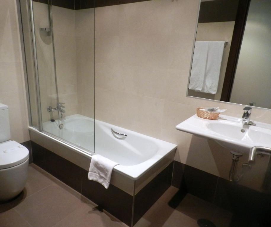 a bathroom with a sink and a tub and a toilet at Hotel Río Hortega in Valladolid