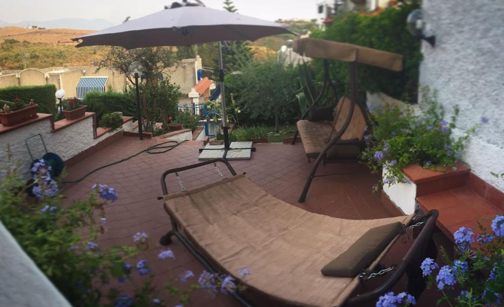 eine Terrasse mit einer Holzbank und einem Sonnenschirm in der Unterkunft Villetta Clorinda in San Nicola Arcella