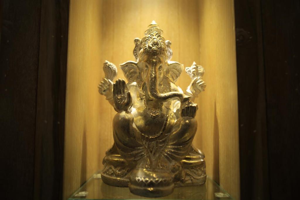 uma estátua de bronze sentada numa prateleira de vidro em Poshtel Ubud em Ubud