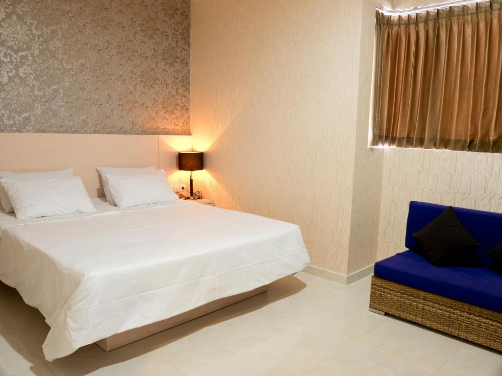 a bedroom with a white bed and a blue chair at SWK 95 Hotel in Surabaya