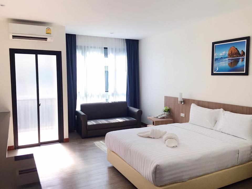sypialnia z dużym białym łóżkiem i krzesłem w obiekcie Orchid Riverview Hotel w mieście Surat Thani