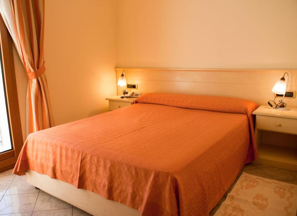 Hotel Stella 2000 في أولبيا: غرفة نوم بسرير ولحاف برتقالي