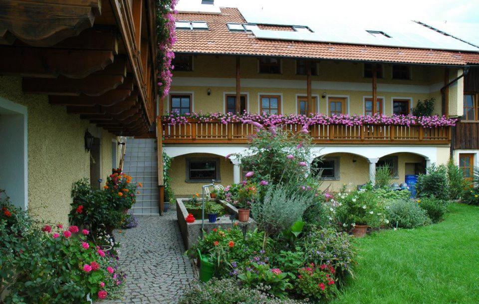 un jardin en face d'un bâtiment fleuri dans l'établissement Ferienhof Löw, à Salzweg