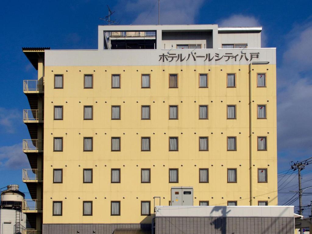 un grand bâtiment jaune avec des écrits chinois sur lui dans l'établissement Hotel Pearl City Hachinohe, à Hachinohe