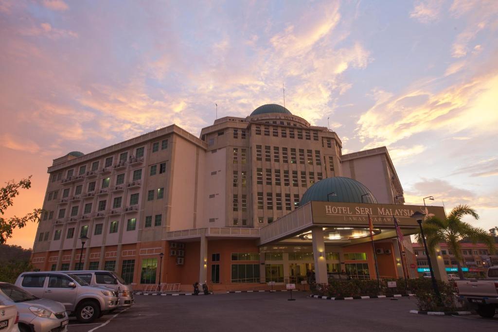 Hotel Seri Malaysia Lawas في لاواس: مبنى كبير وامامه موقف سيارات