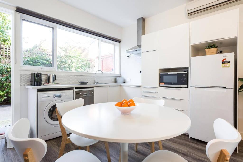 a white kitchen with a white table and chairs at Your Home Away from Home in Melbourne