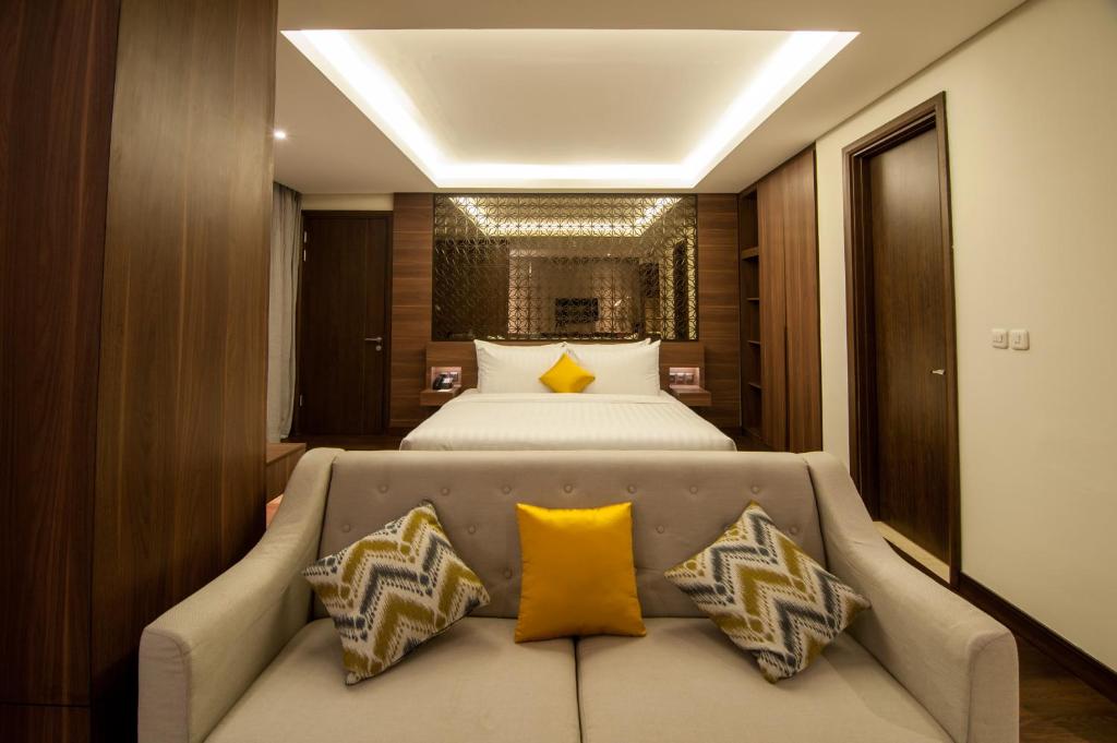 um quarto com uma cama e um sofá com almofadas amarelas em Grand Soll Marina Hotel em Tangerang