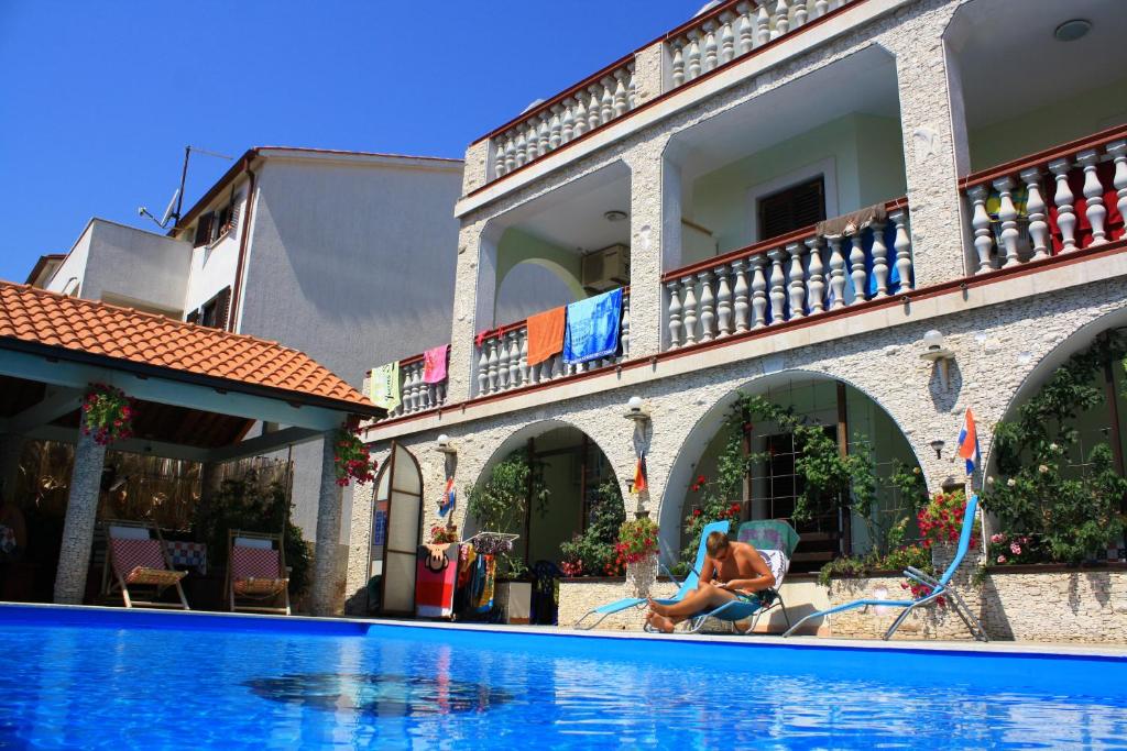 a man playing in a swimming pool next to a building at Apartments & Rooms Lo & Mar in Medulin