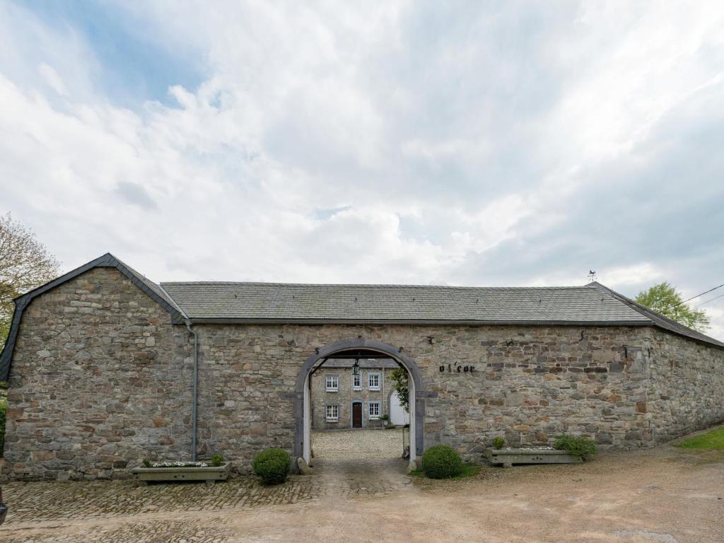 um grande edifício de pedra com uma porta em arco em Medieval farmhouse with private garden em Waimes