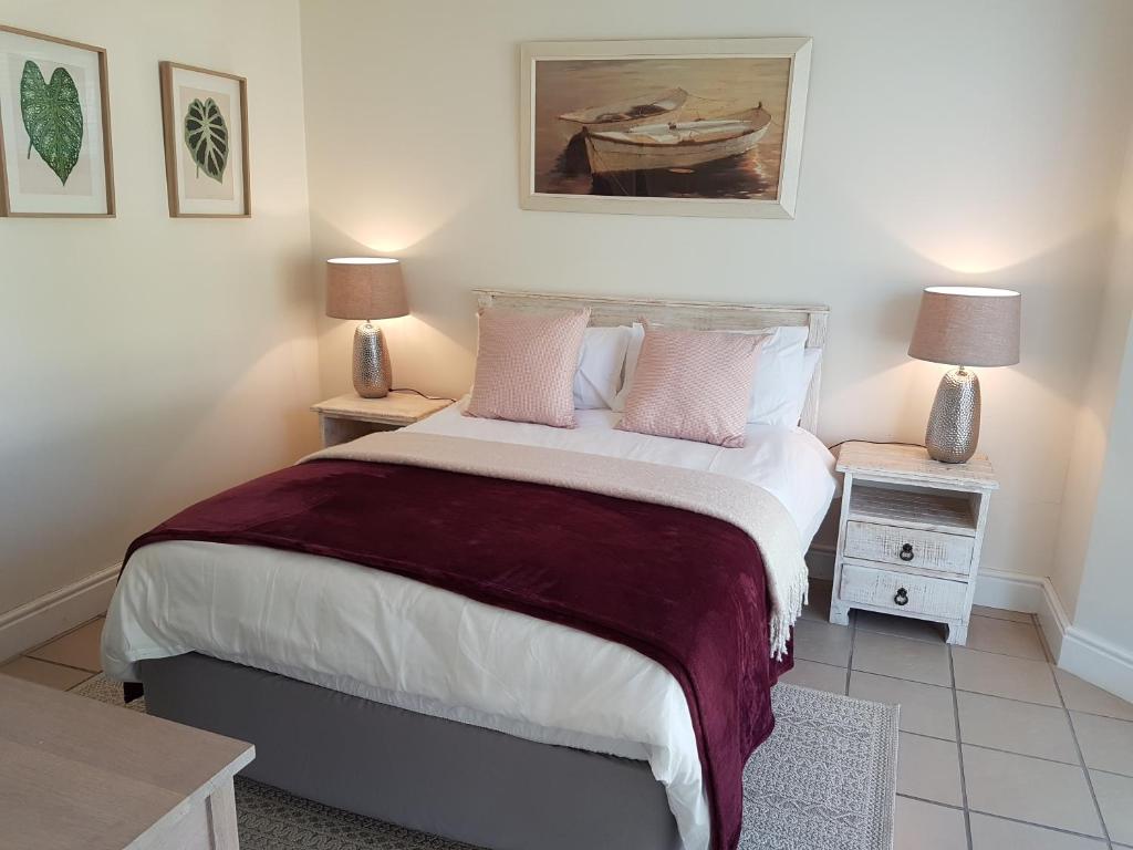 1 dormitorio con 1 cama con 2 mesas y 2 lámparas en Thirty River Club Villas managed by The Paper Fig House en Plettenberg Bay