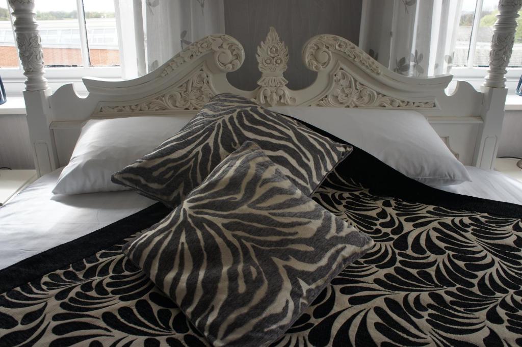 Cama blanca con edredón y almohadas blancos y negros en York House Hotel en Wakefield
