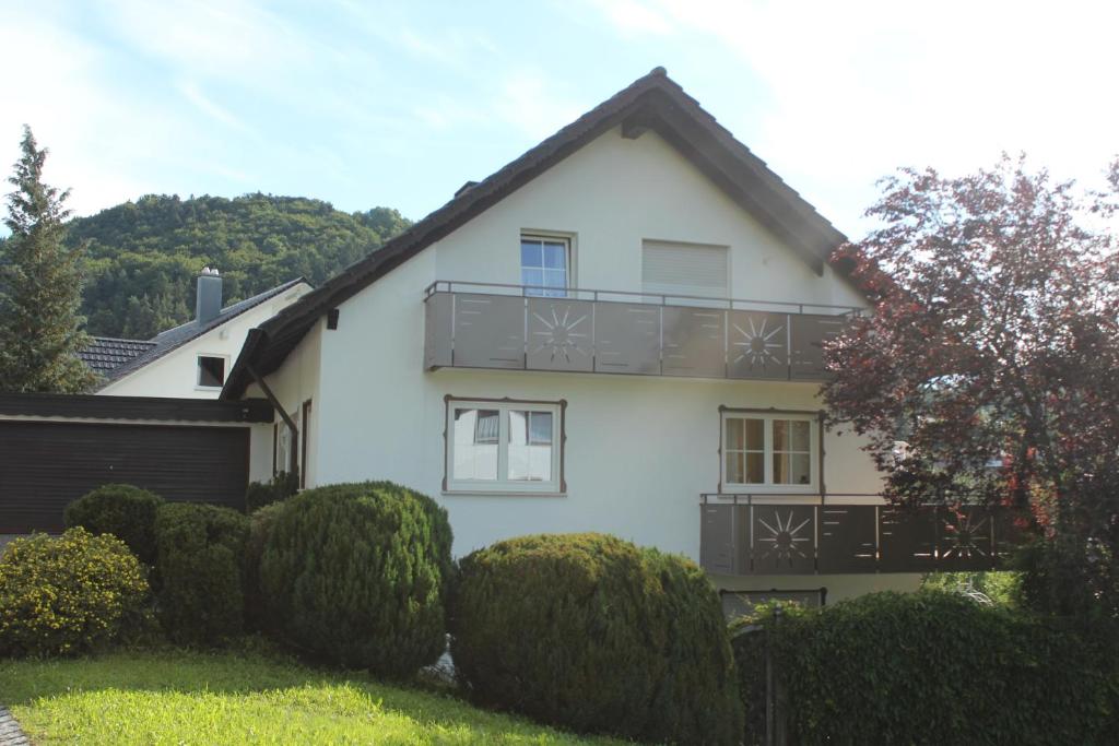 a white house with a balcony and some bushes at Ferienwohnung Waltraud in Tieringen