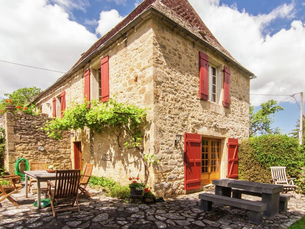 an old stone house with red shutters and a picnic table at Farmhouse in Saint Cybranet with Private Garden in Saint-Cybranet