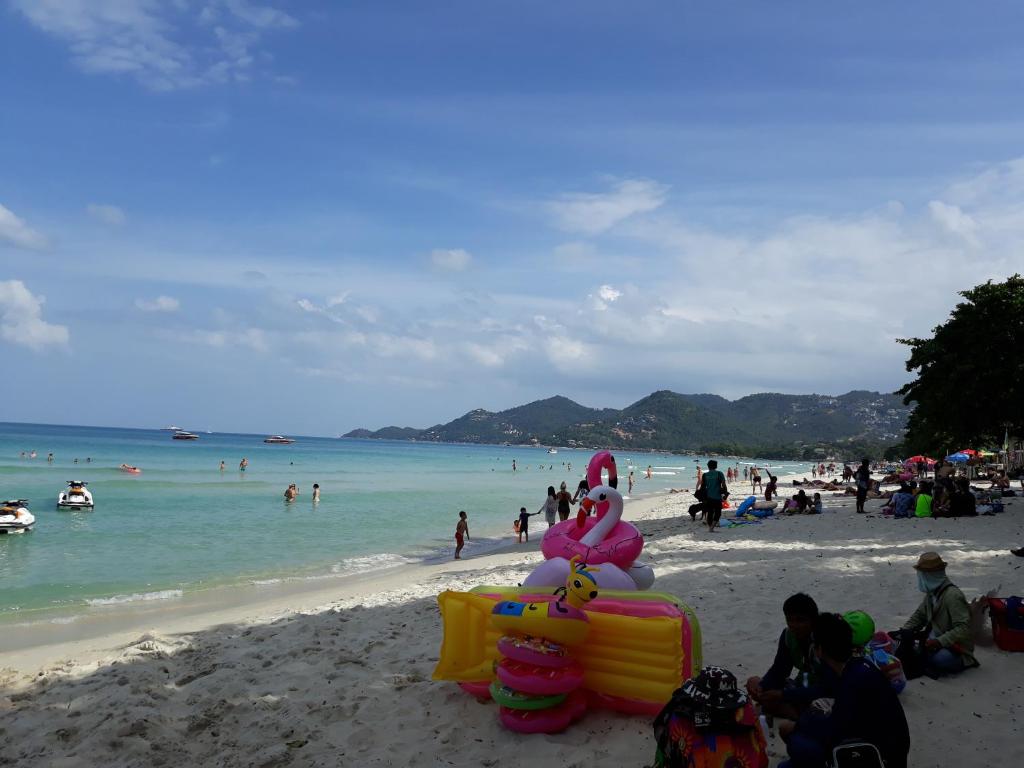 un groupe de personnes assises sur une plage dans l'établissement Samui Green Hotel, à Chaweng