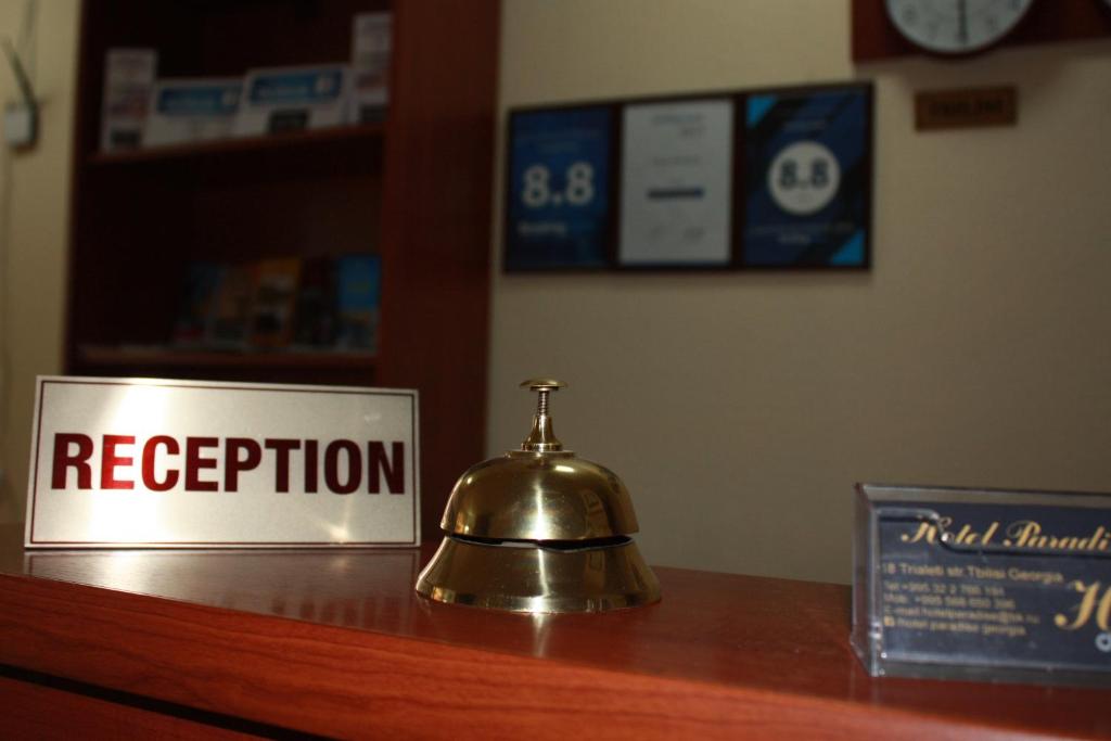 una campana sentada en un mostrador con una señal de recepción en Paradise Hotel, en Tiflis
