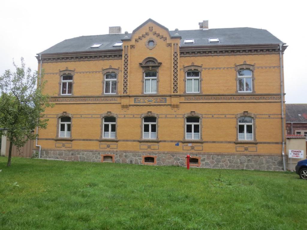 un gran edificio amarillo con un reloj. en Zimmervermietung zum See, en Wolteritz
