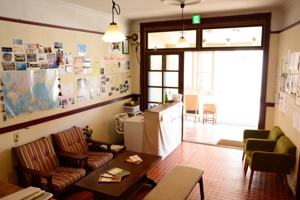 a living room with a refrigerator and a table and chairs at Guesthouse Tomaru in Takayama