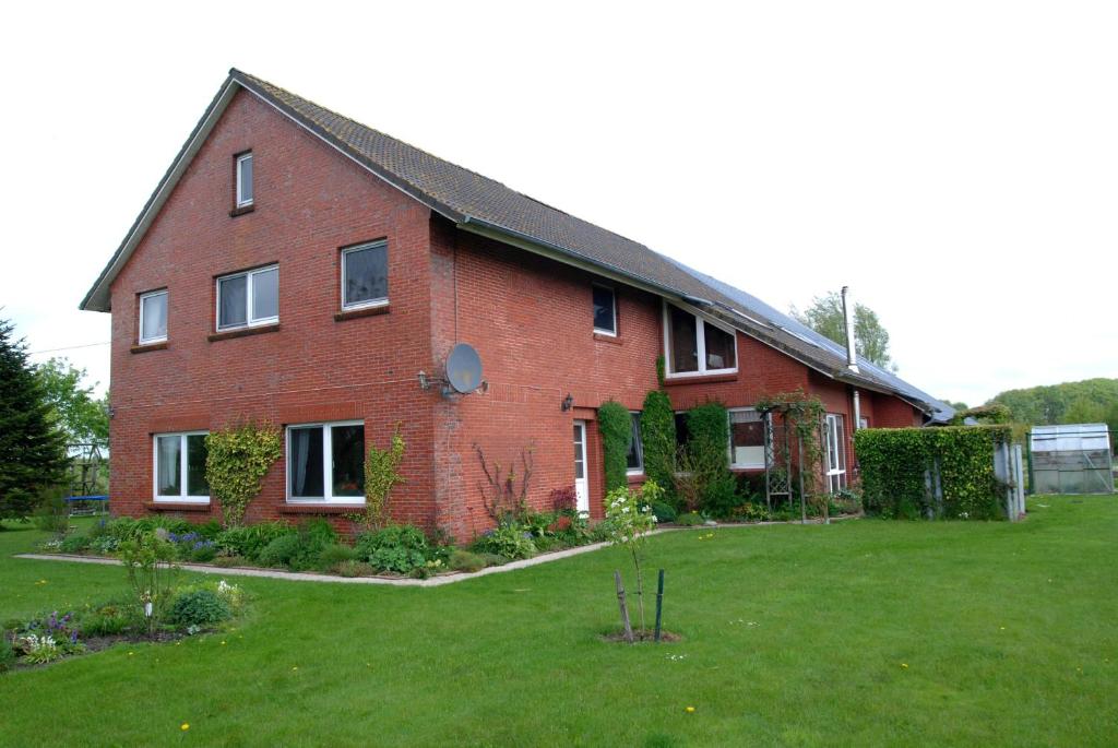 ein großes rotes Backsteinhaus mit einem grünen Hof in der Unterkunft Schwalbenhof in Norden