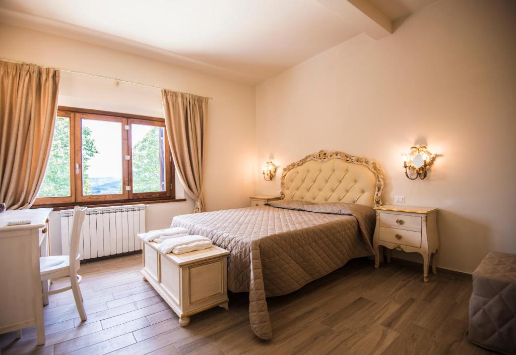 a bedroom with a bed and a table and windows at Il FEUDO in San Gimignano