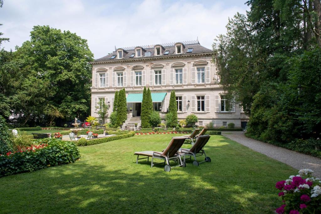 une grande maison avec des chaises dans la cour dans l'établissement Hotel Belle Epoque, à Baden-Baden