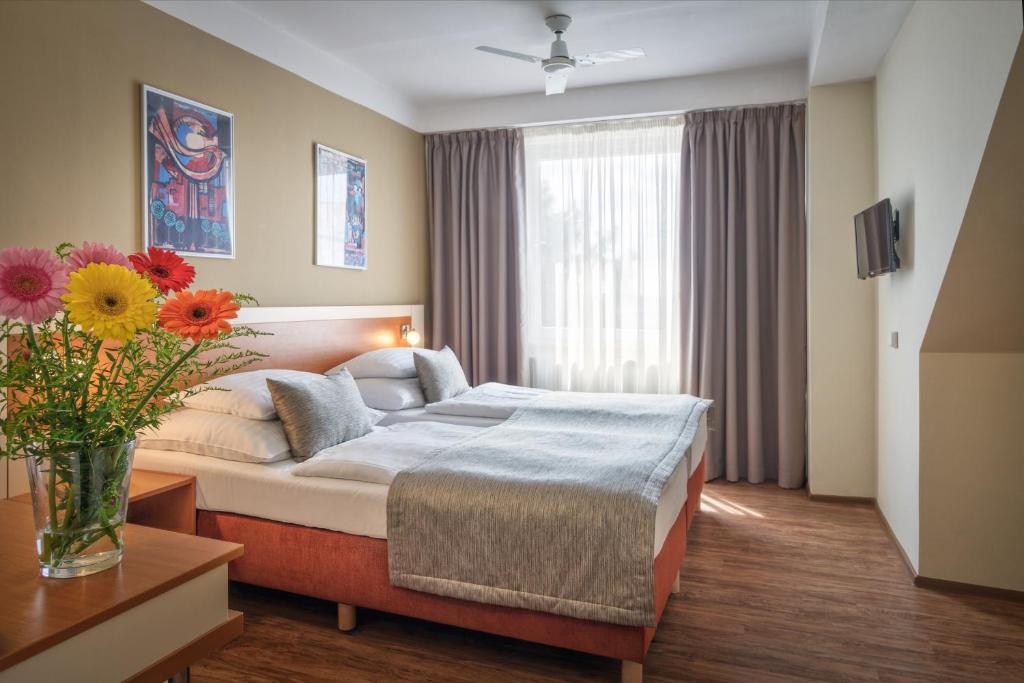 una habitación de hotel con una cama y un jarrón de flores en Hotel Aida en Praga