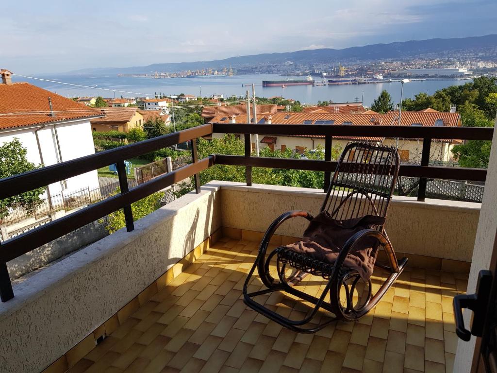a rocking chair sitting on a balcony with a view at Appartamento Nerio in Muggia