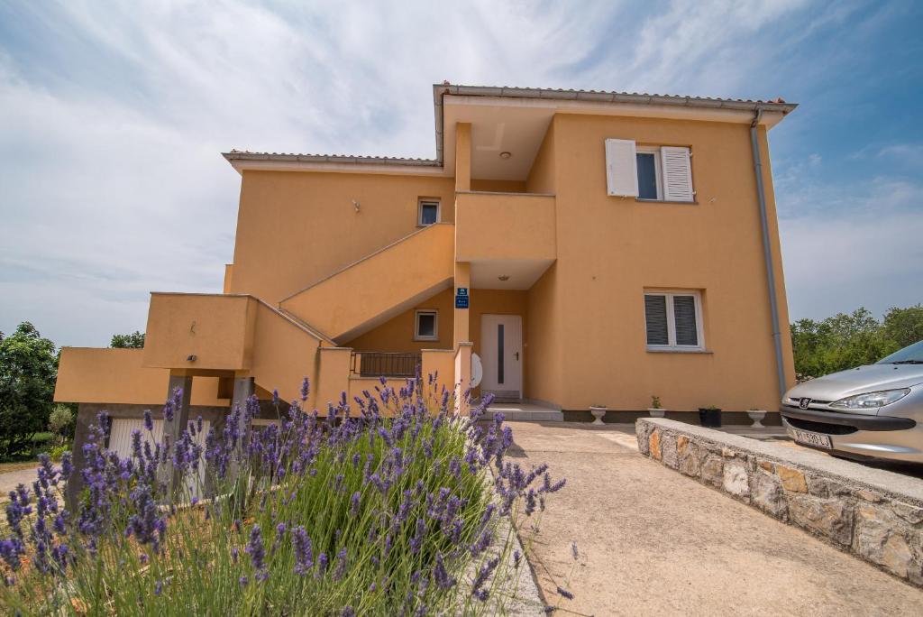 a house with purple flowers in front of it at Apartments Sanjin in Kornić