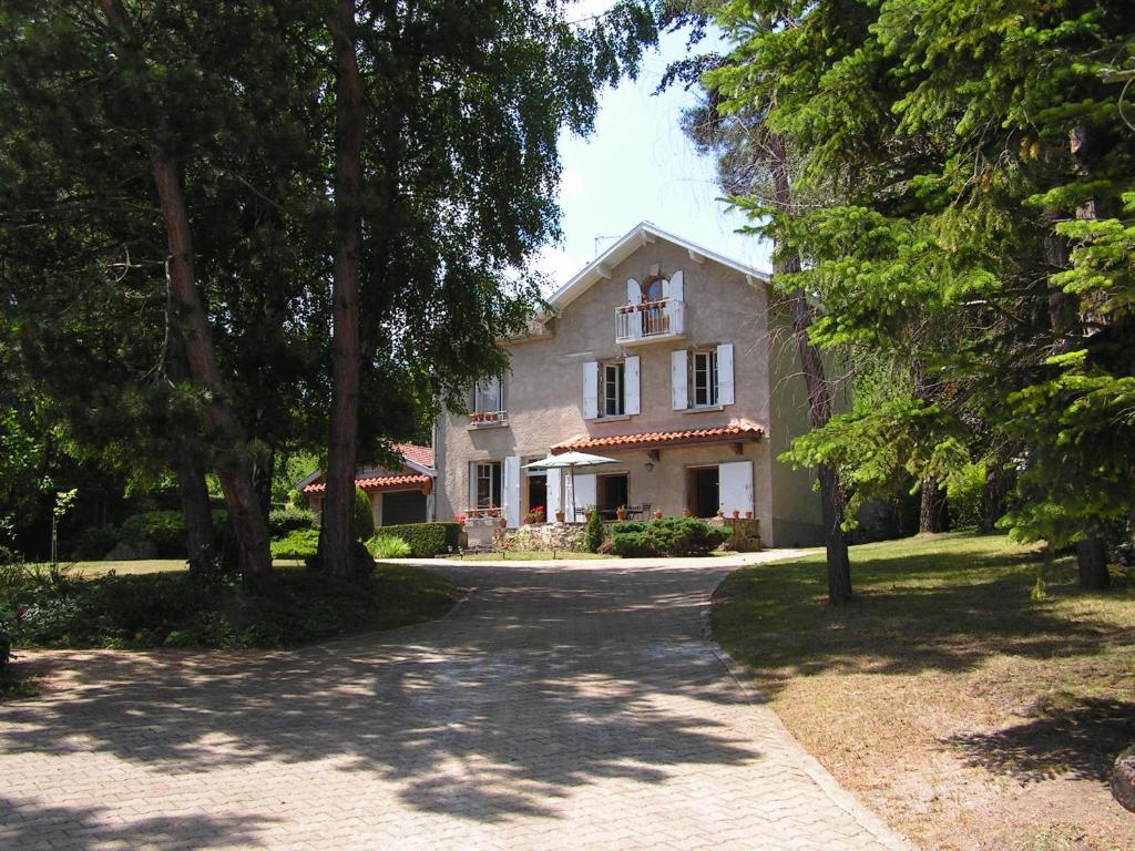 une grande maison blanche avec des arbres devant elle dans l'établissement La Maison de Mireille, au Puy-en-Velay