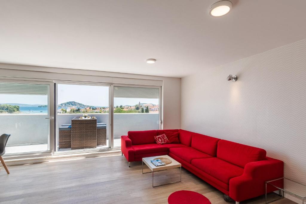 a living room with a red couch and a large window at Apartments Sunrise in Preko