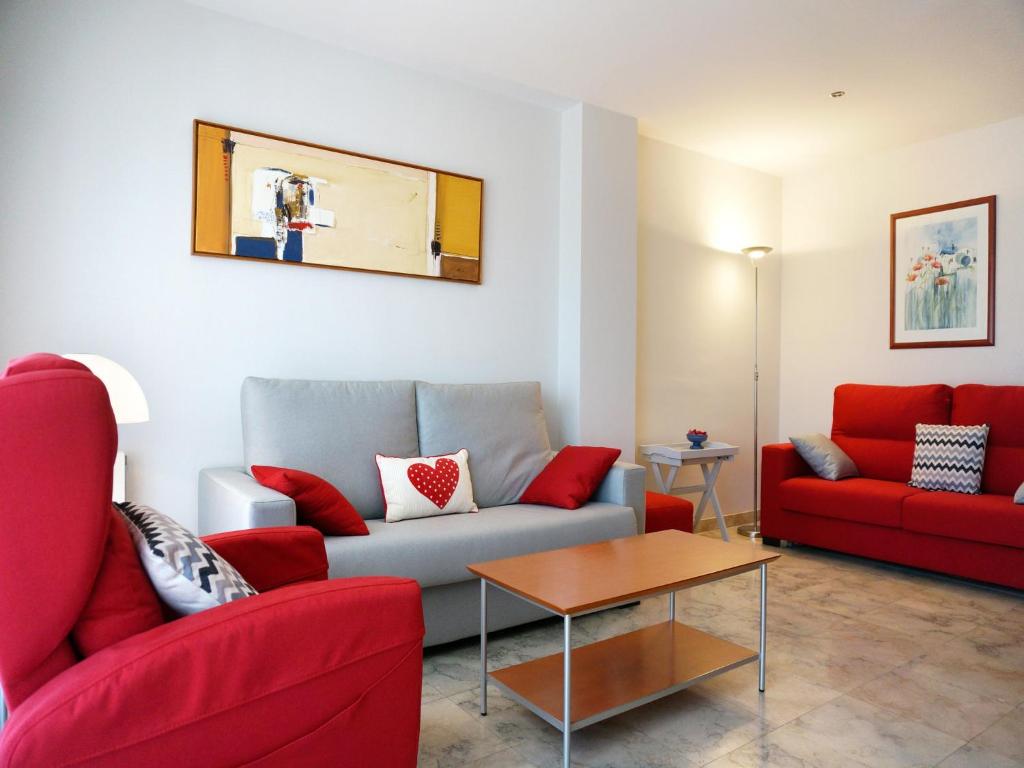 una sala de estar con 2 sofás rojos y una mesa. en Llevant I Ponent, en Palamós