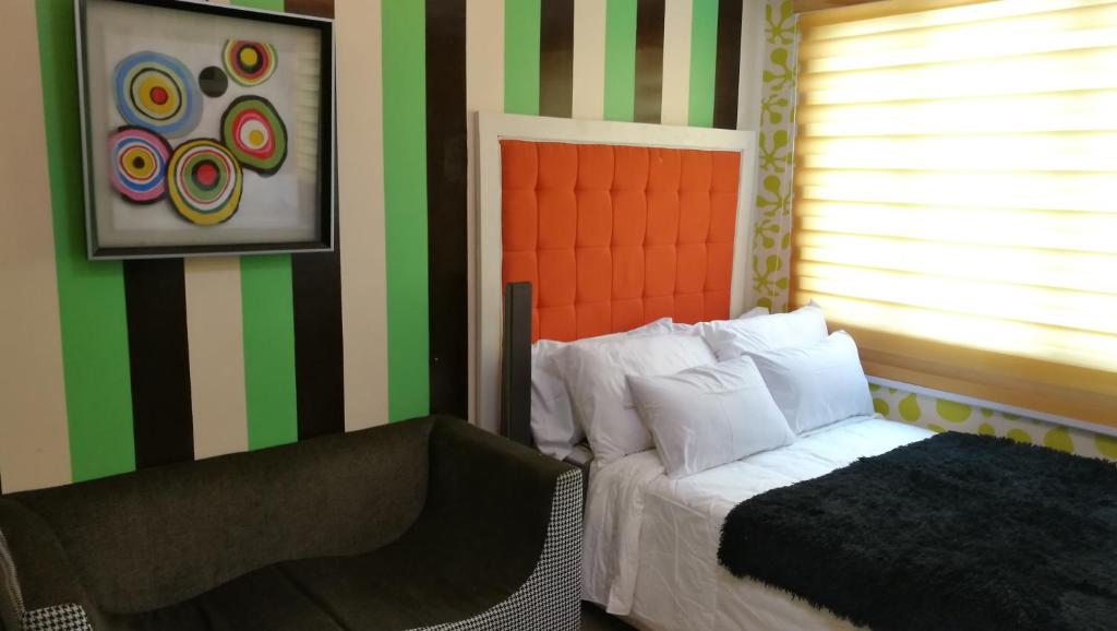 ein Schlafzimmer mit grün und orange gestreiften Wänden und einem Bett in der Unterkunft M-Place South Triangle in Manila