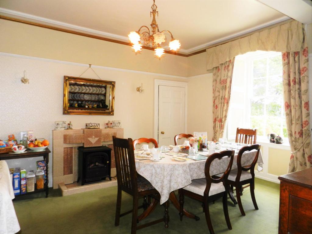 a dining room with a table and chairs and a fireplace at Gogarth hall Farm holidays in Pennal