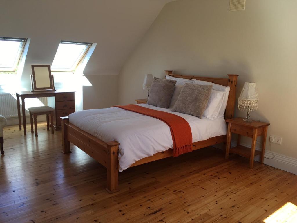 a bedroom with a bed and a desk and windows at Burrowlodge in Kilfenora