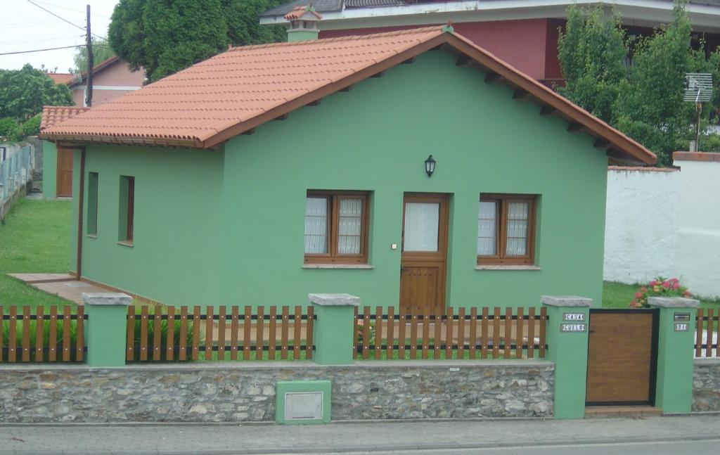 ein kleines grünes Haus mit einem Holzzaun in der Unterkunft Casa Güelo in Muros de Nalón