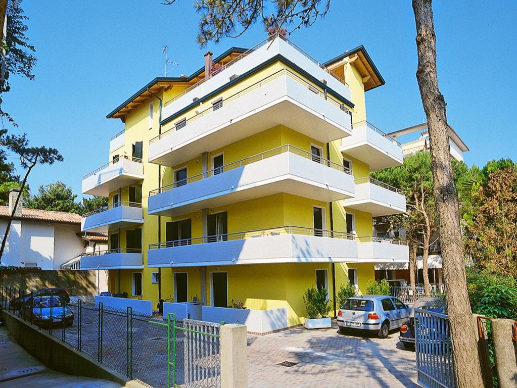un edificio amarillo y blanco con coches estacionados frente a él en Residence Solemar - Agenzia Cocal, en Caorle