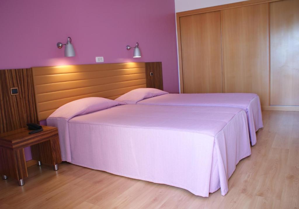 a bedroom with a large white bed with a wooden headboard at Hotel O Novo Principe in Almeirim
