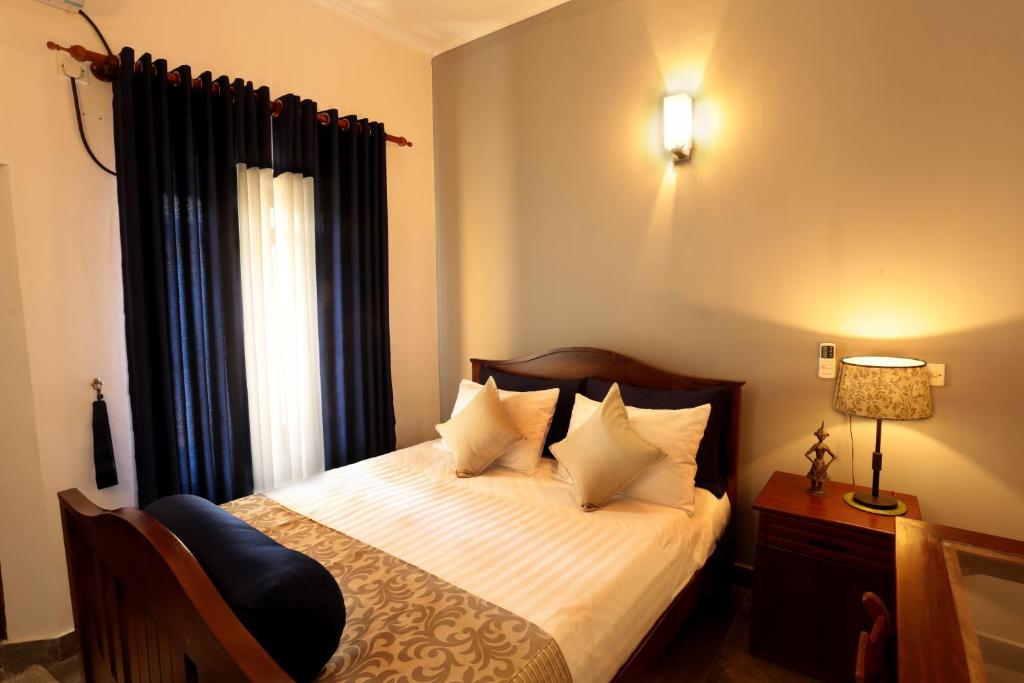 una camera da letto con un letto con lenzuola bianche e una finestra di Mitrayu a Nugegoda