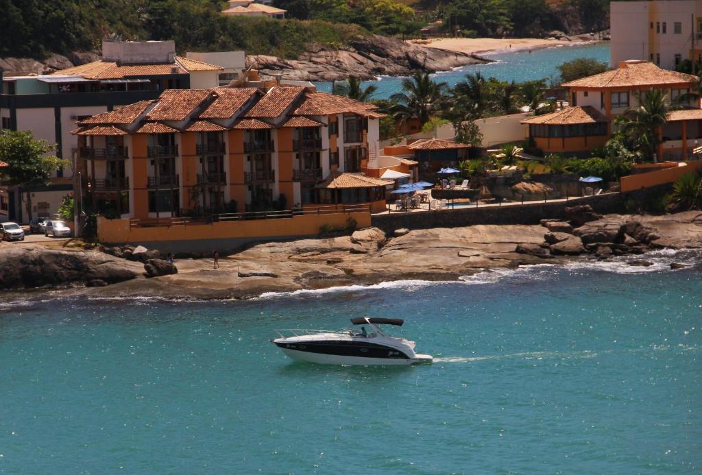 a boat in the water in front of a resort at Hotel Pontal das Rochas in Iriri
