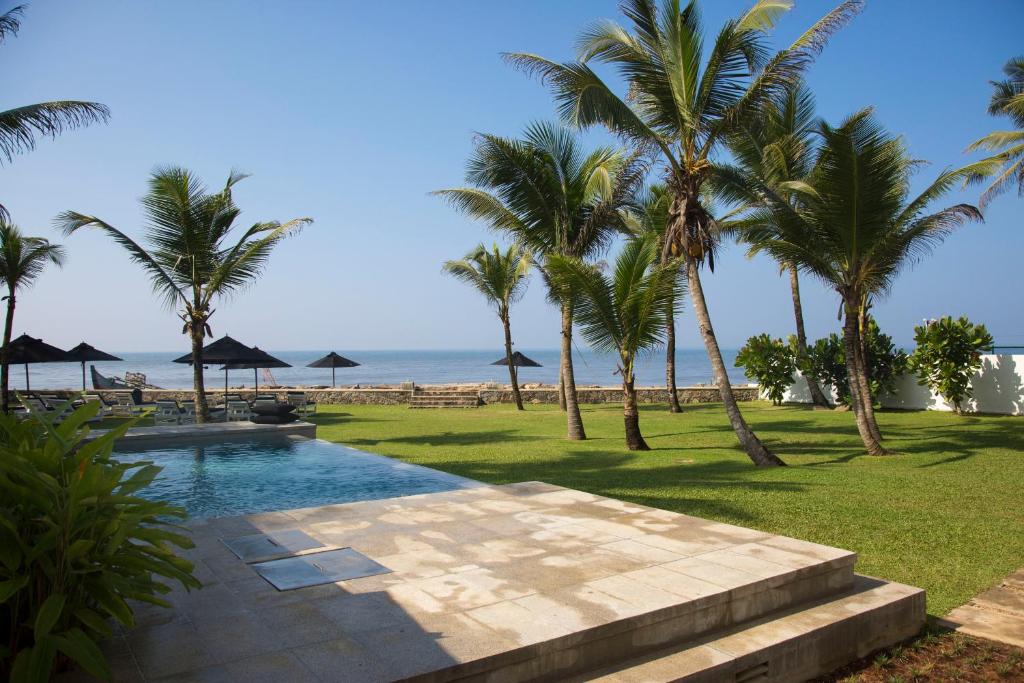 uma piscina com palmeiras e o oceano em Arabella on Boossa em Galle