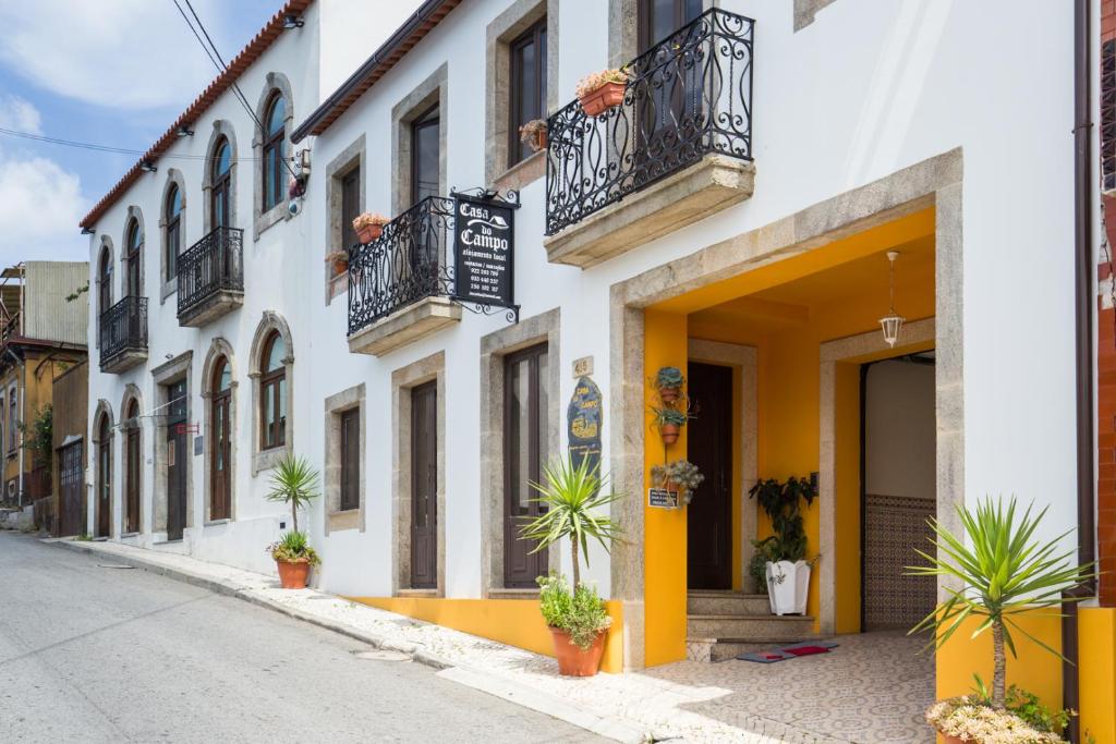 Casa do Campo AL في Caldas de São Jorge: شارع فيه مباني بيضاء وصفراء فيه نباتات الفخار