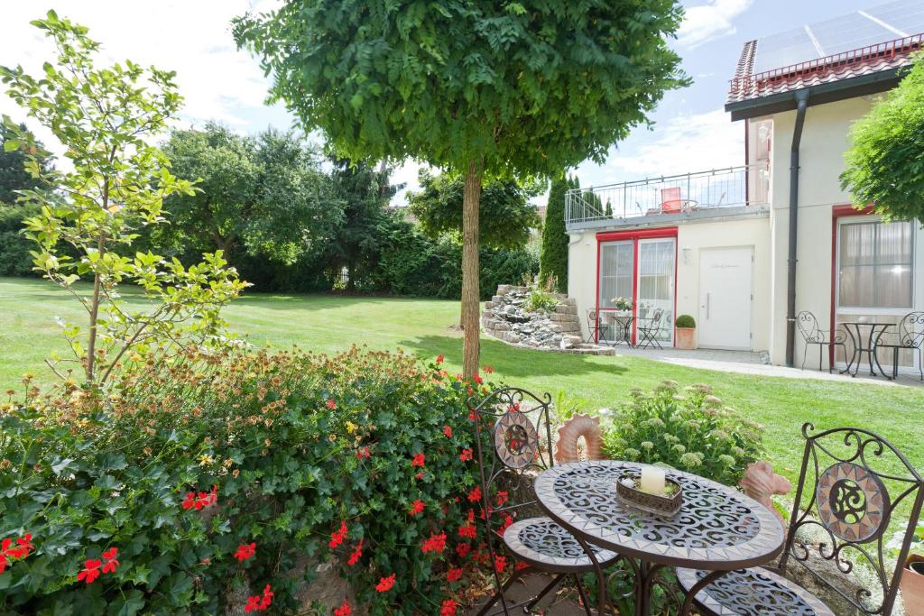 einen Garten mit einem Tisch, Stühlen und Blumen in der Unterkunft Engelhard Das Landhotel Garni in Kirchheim am Ries