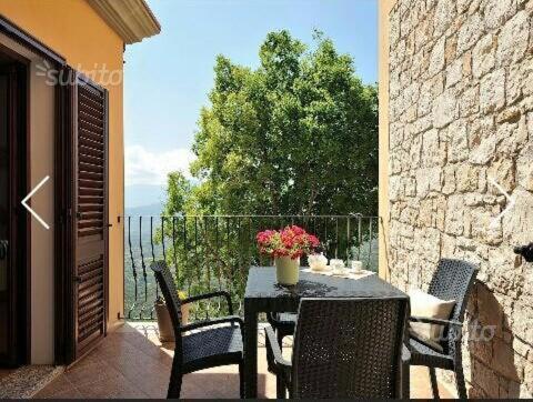 un patio con tavolo e sedie sul balcone. di Usuonu a Baunei