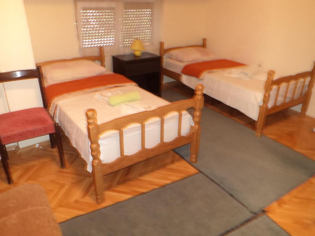a bedroom with two beds and a table and a chair at Hotel Le Village in Skopje